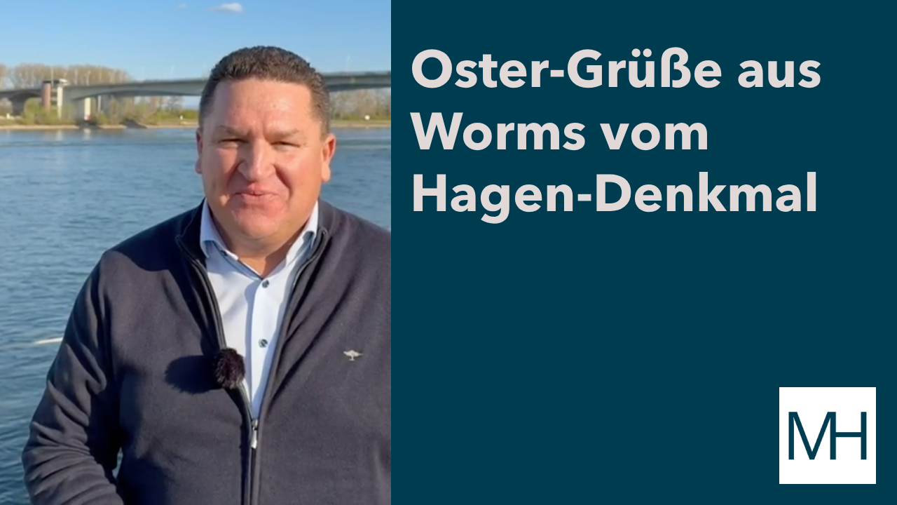 Marcus Held am Rheinufer in Worms vor einer Brücke mit Ostergrüßen vom Hagen-Denkmal in Rheinland-Pfalz