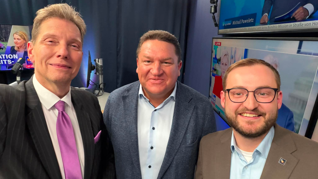 Von links nach rechts: Moderator Andreas Dorfmann, Marcus Held und NIUS-Reporter Philippe Fischer gemeinsam im NIUS Studio während einer politischen Sendung zu aktuellen Entwicklungen in Deutschland.